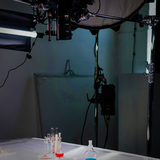 A photo studio featuring camera and lighting equipment as well as chemistry test tubes.